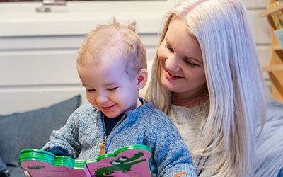 Bilde av en barnehageansatt som leser bok til en liten gutt